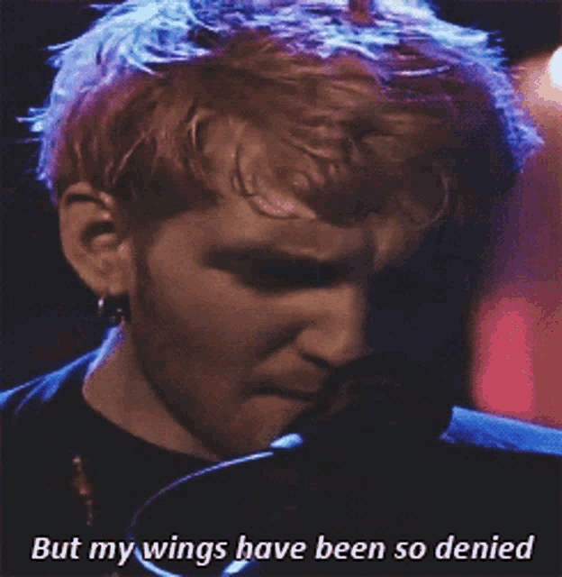 a man singing into a microphone with the words " but my wings have been so denied " next to him