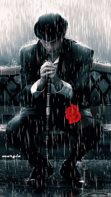 a man is kneeling down in the rain with a red rose