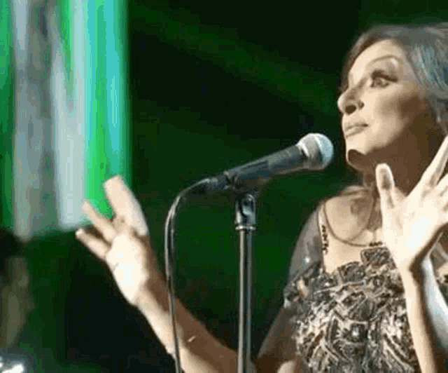 a woman is singing into a microphone with her hands outstretched