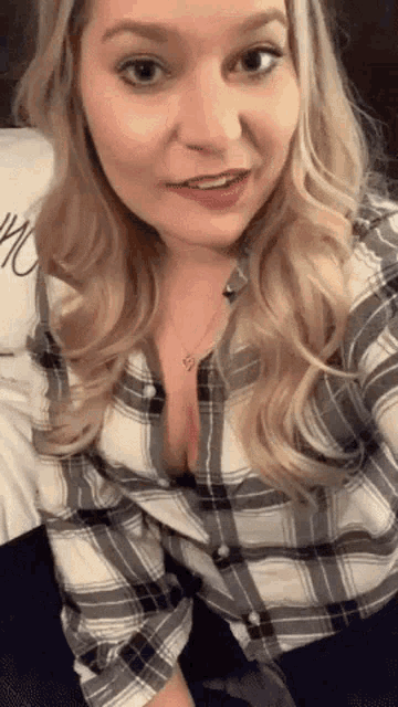 a woman in a plaid shirt is sitting on a bed