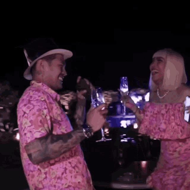 a man in a top hat and a woman in a pink dress toasting with champagne glasses