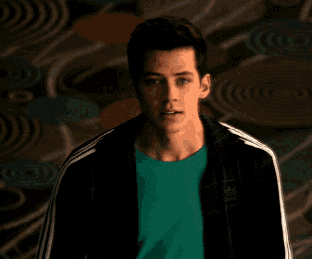 a young man wearing a green shirt and an adidas jacket