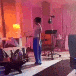 a person is standing in a living room with purple lights .