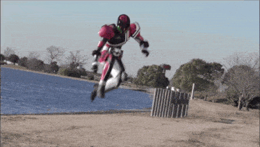 a person in a robot costume jumps in the air near a body of water