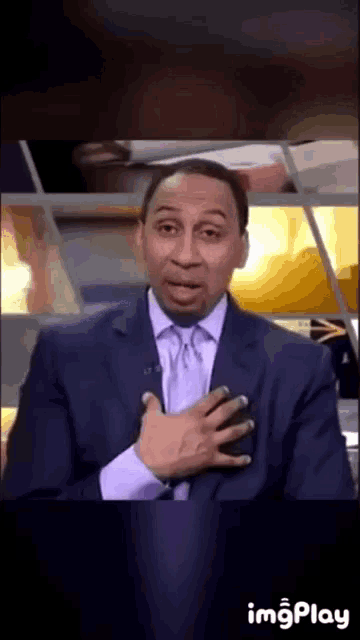 a man in a suit and tie is making a funny face with his hand on his chest