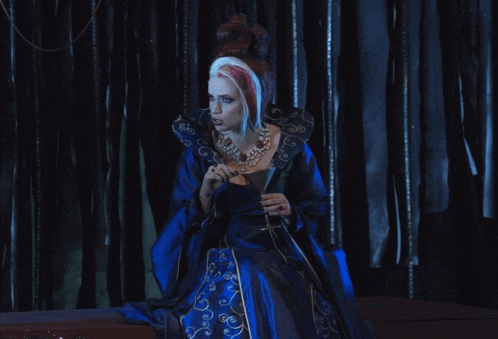 a woman in a blue dress holds a glass of wine