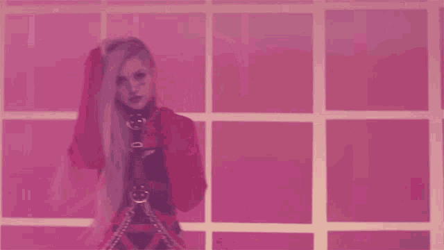 a woman with long pink hair is standing in front of pink squares
