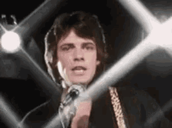 a man is singing into a microphone on a stage in front of a crowd .