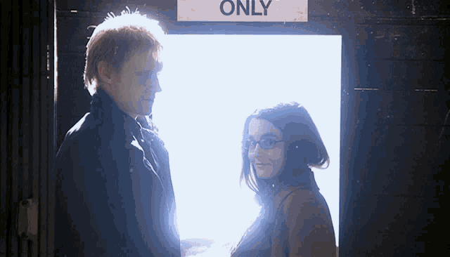 a man and a woman standing in front of a sign that says only
