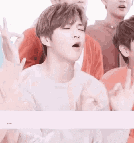 a group of young men are sitting in a row with their mouths open and their hands up .
