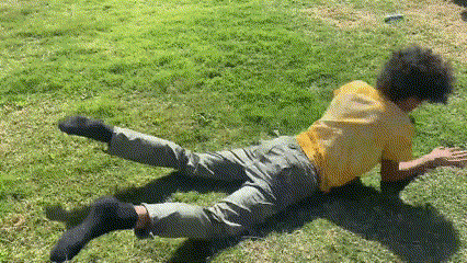 a man in a yellow shirt is laying on his back in the grass