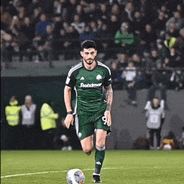 a soccer player in a green jersey is kicking a soccer ball on the field .
