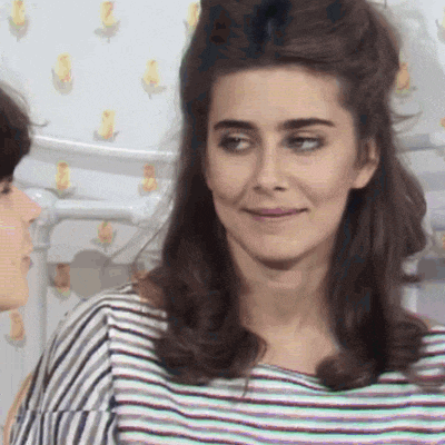 a woman in a striped shirt is smiling and looking at another woman