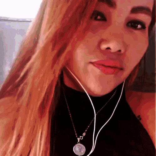 a woman wearing headphones and a necklace with a coin on it