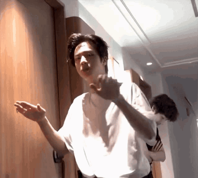 a man in a white shirt stands in front of a wooden door