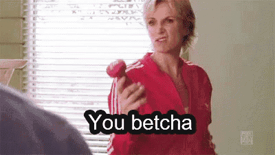 a woman in a red jacket is holding a red apple in her hand and says `` you betcha '' .