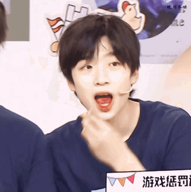 a young man with a microphone in his mouth eating a strawberry