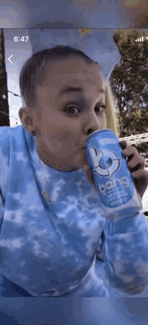a girl is drinking a can of bang energy drink .