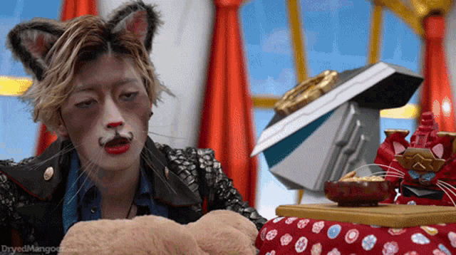 a man with cat ears and a mustache is looking at a stuffed animal
