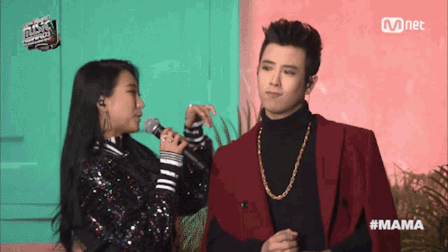 a woman singing into a microphone next to a man with the hashtag mama