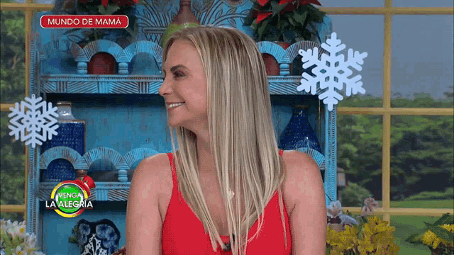 a woman in a red dress is smiling in front of a blue shelf with snowflakes on it