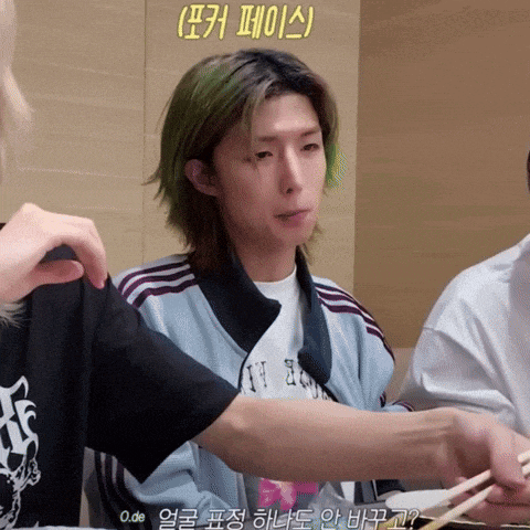 a man with green hair is holding chopsticks and wearing a shirt that says ' o.de ' on it