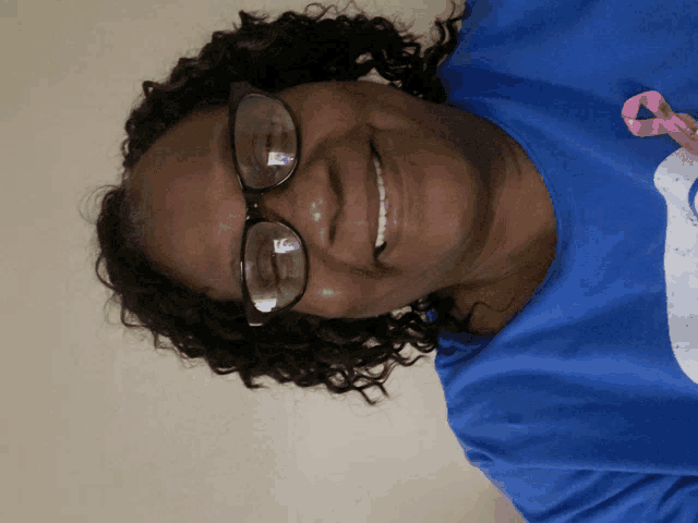 a smiling woman wearing glasses and a blue shirt