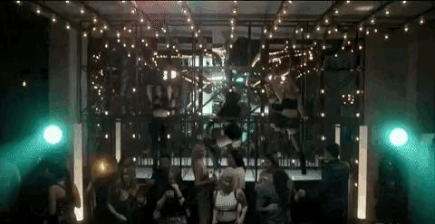 a group of people are dancing in a dark room with string lights hanging from the ceiling