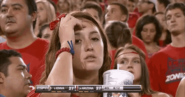 a woman holds a cup in her hand while watching a game on espn