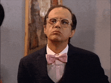 a man wearing glasses and a pink bow tie looks serious