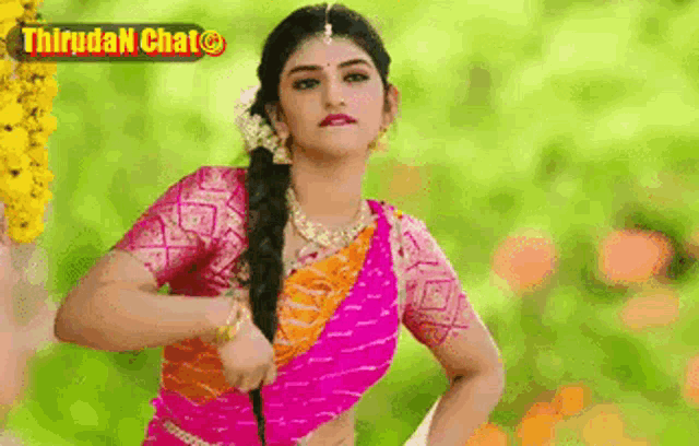a woman in a pink and orange saree is dancing in front of a green background