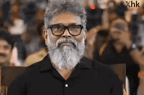 a man with a beard wearing glasses and a black shirt
