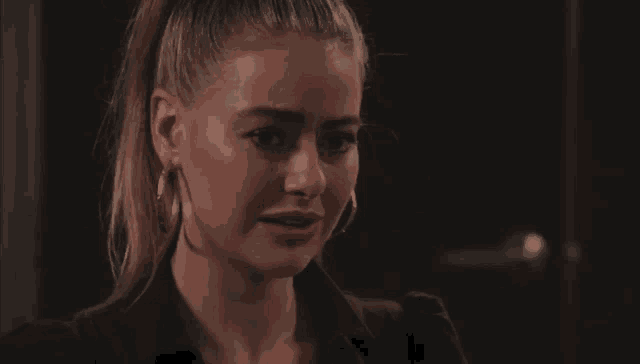 a woman wearing hoop earrings and a black shirt is crying