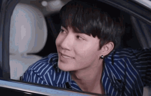 a young man is sitting in the back seat of a car looking out the window .
