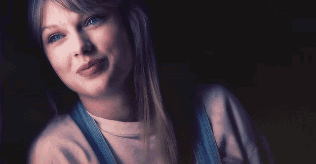 a close up of a woman 's face with overalls and a white shirt