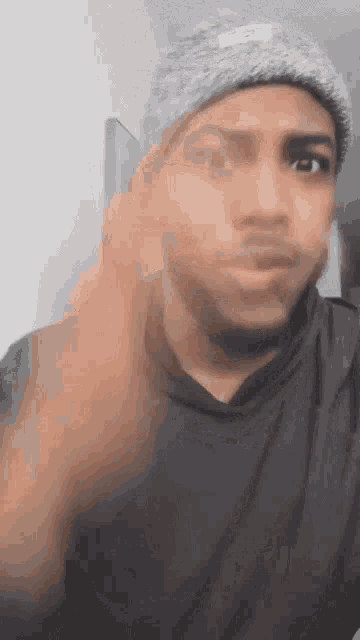 a man wearing a gray hat and a black shirt is making a face