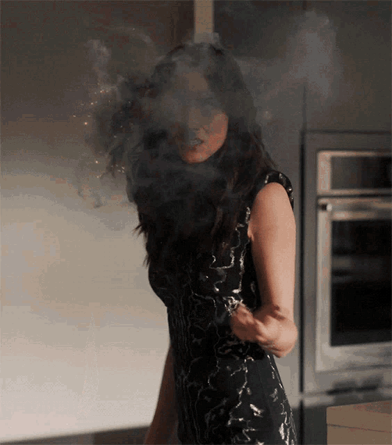 a woman in a black dress is covered in smoke