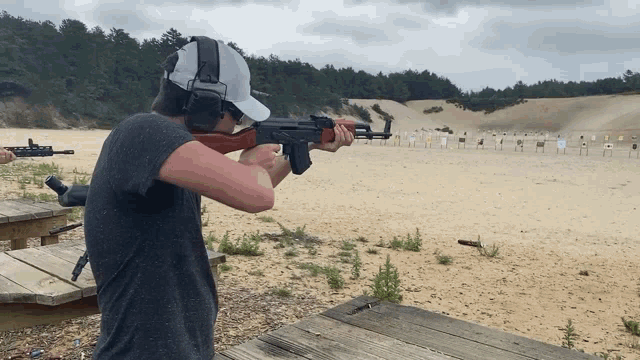 a man wearing headphones and a white hat is holding a rifle