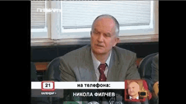 a man in a suit and tie is sitting at a table with a sign that says 21 on it
