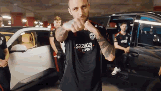 a man wearing a shirt that says sazka esport is pointing at the camera