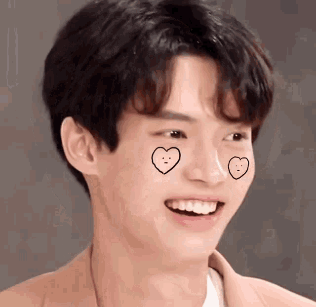a young man with hearts drawn on his face is smiling .