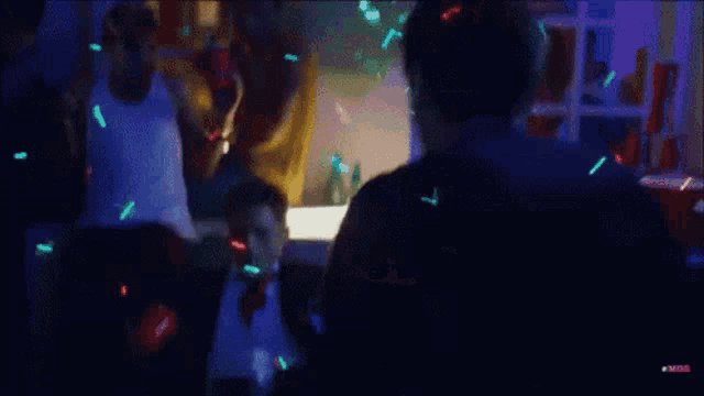 a group of people are dancing in a dark room with confetti flying around
