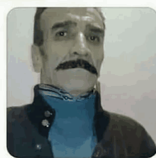 a man with a mustache is taking a selfie .