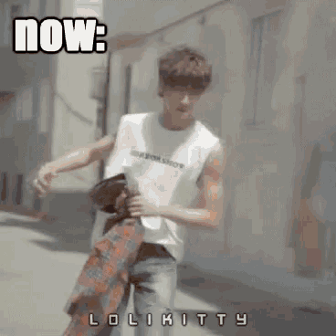 a man in a white tank top is walking down a street and the words now are above him