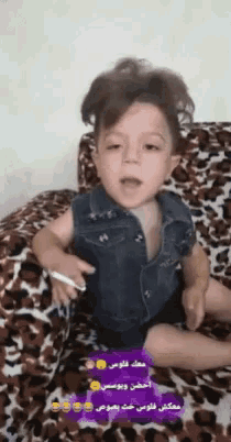 a little boy is sitting on a leopard print couch