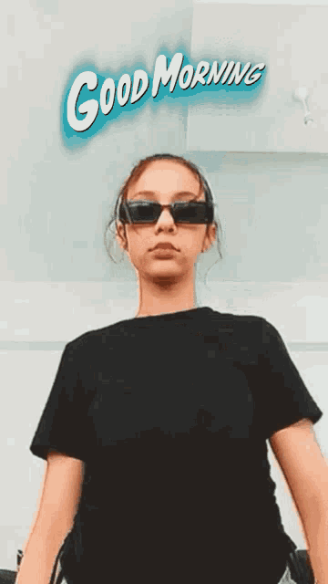 a girl wearing sunglasses is taking a selfie with the words good morning behind her .