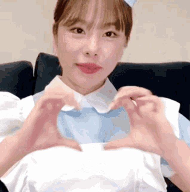 a woman in a maid costume is making a heart with her hands .