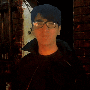 a man wearing glasses stands in front of a brick building