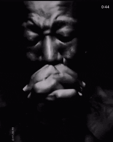 a black and white photo of a man with his hands folded and the time of 1:43