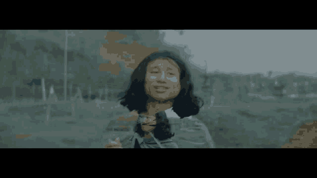 a woman with long hair is standing in a field holding a stick .